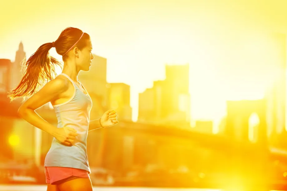 A woman in motion, running with determination in front of a bustling city skyline under a clear sky.